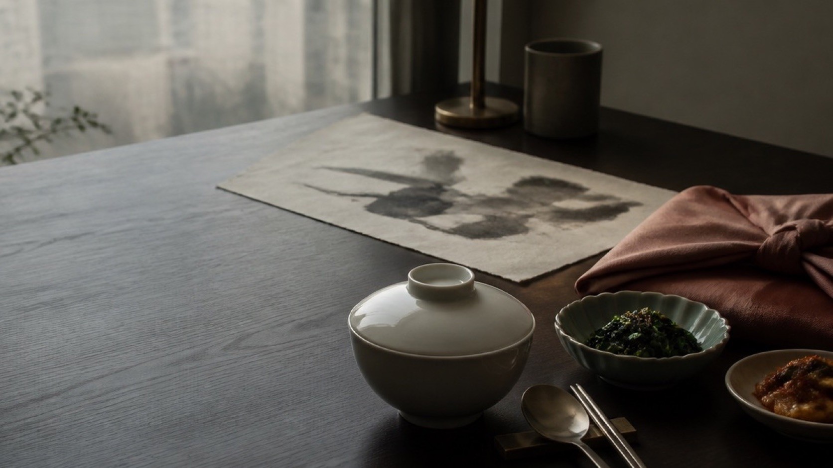 A quiet Korean family table with porcelain, banchan, bojagi cloth and hanji paper