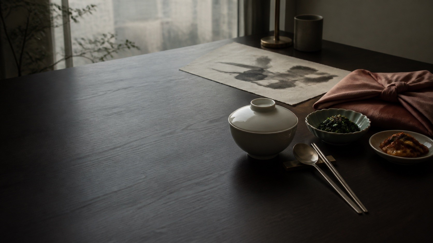 A quiet Seoul table with Korean porcelain, banchan, stainless cutlery, bojagi cloth and hanji in morning light
