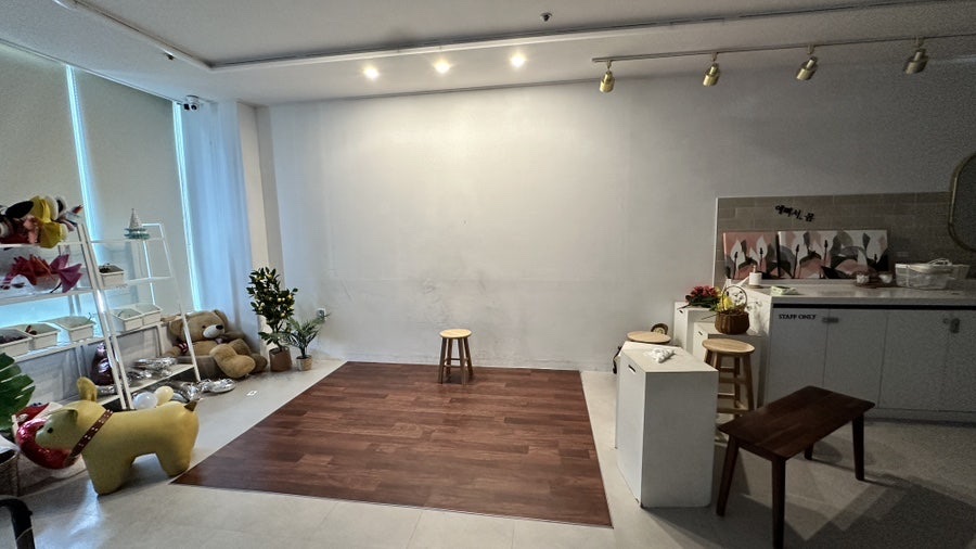 Empty self-service photo studio with backdrop, chairs and props along one wall