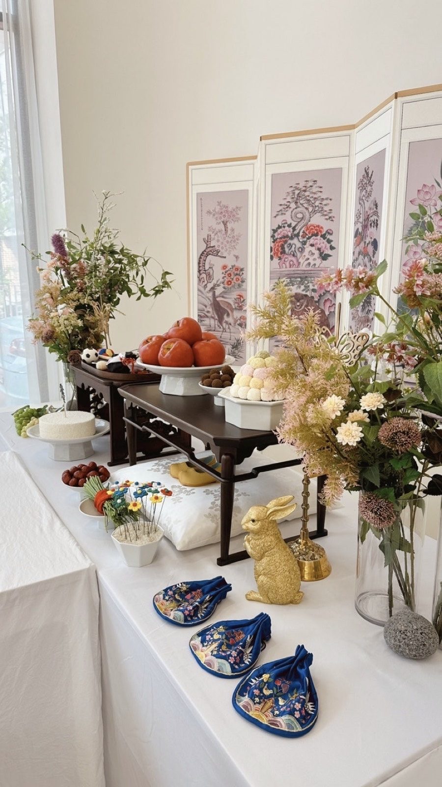 Traditional Korean first-birthday table with a folding screen, flowers and ceremonial props