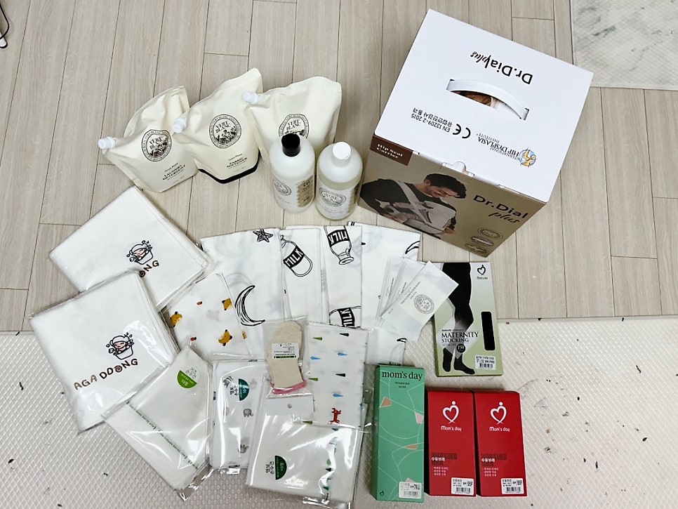 Carrier box, baby cloths, bath items and detergent bottles from the fair laid out at home