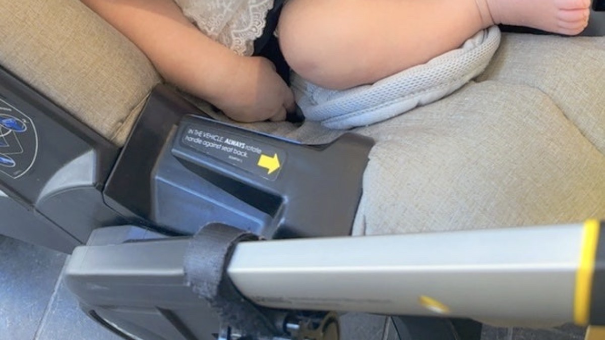 Close crop from a newborn's first outing showing small legs and the infant carrier frame, with the face outside the image