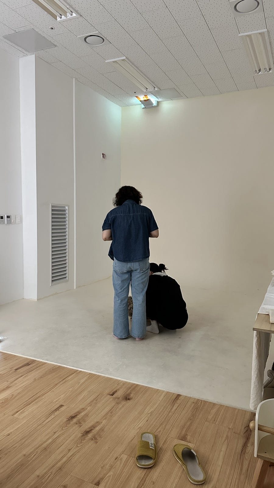 Two studio workers seen from behind while preparing a newborn photography setup