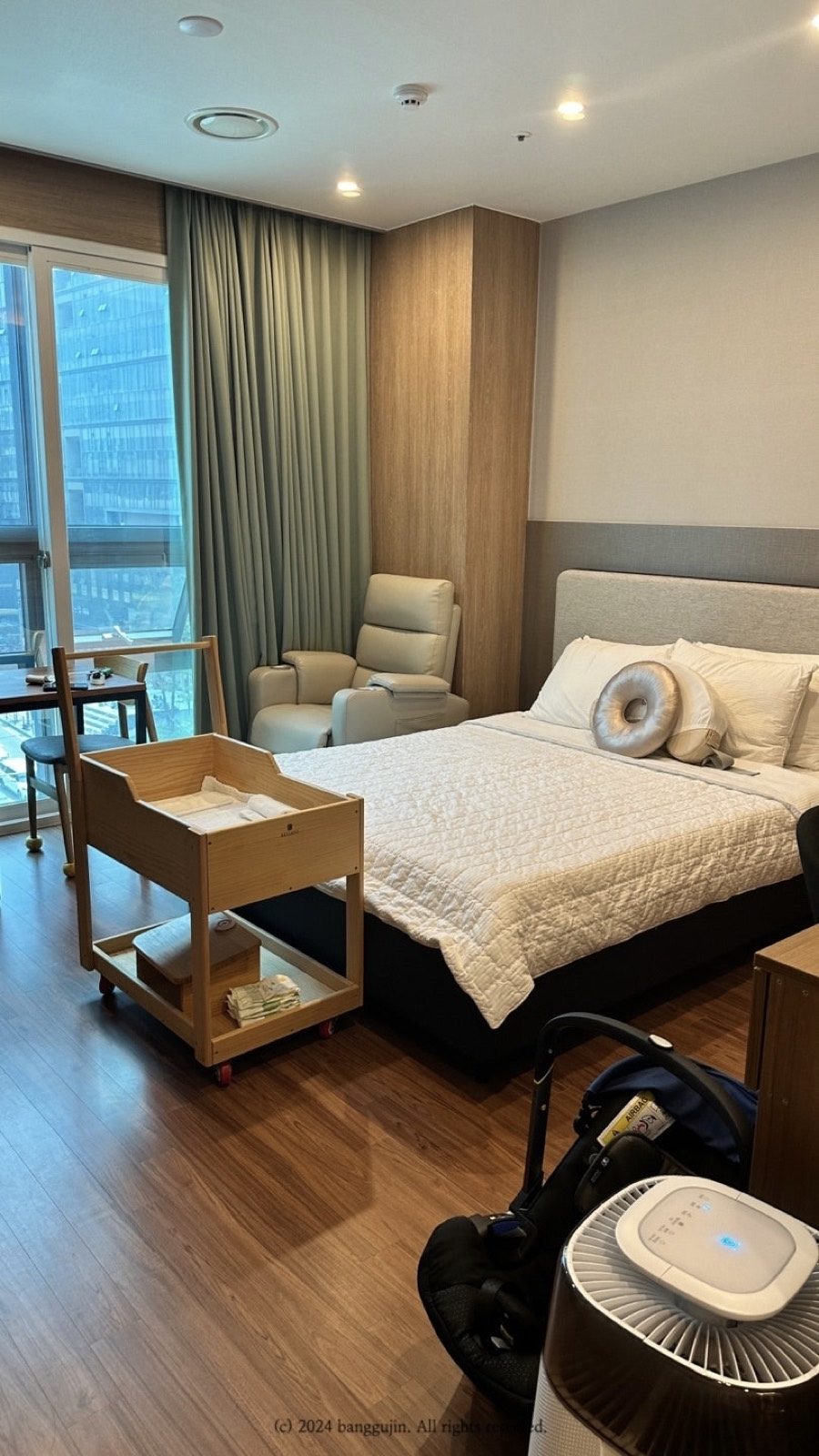 A private postpartum care centre room with a bed, window and recliner chair