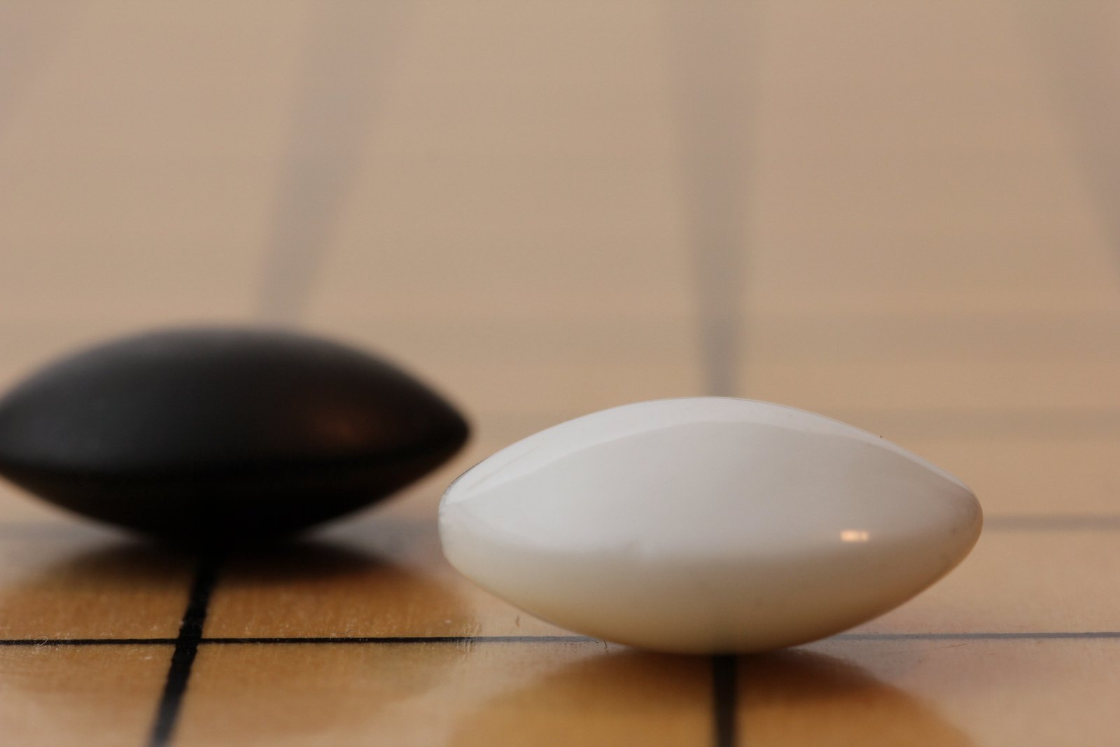 Close-up of one black and one white baduk stone on a wooden board