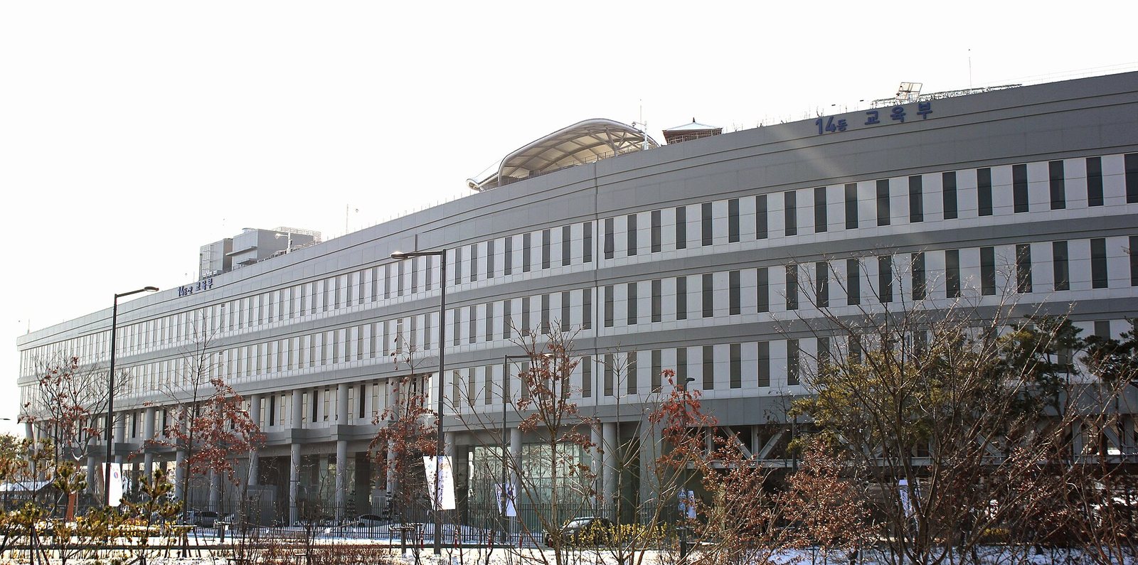 The long grey Ministry of Education building in the Government Complex Sejong, with bare winter trees and a light dusting of snow in front