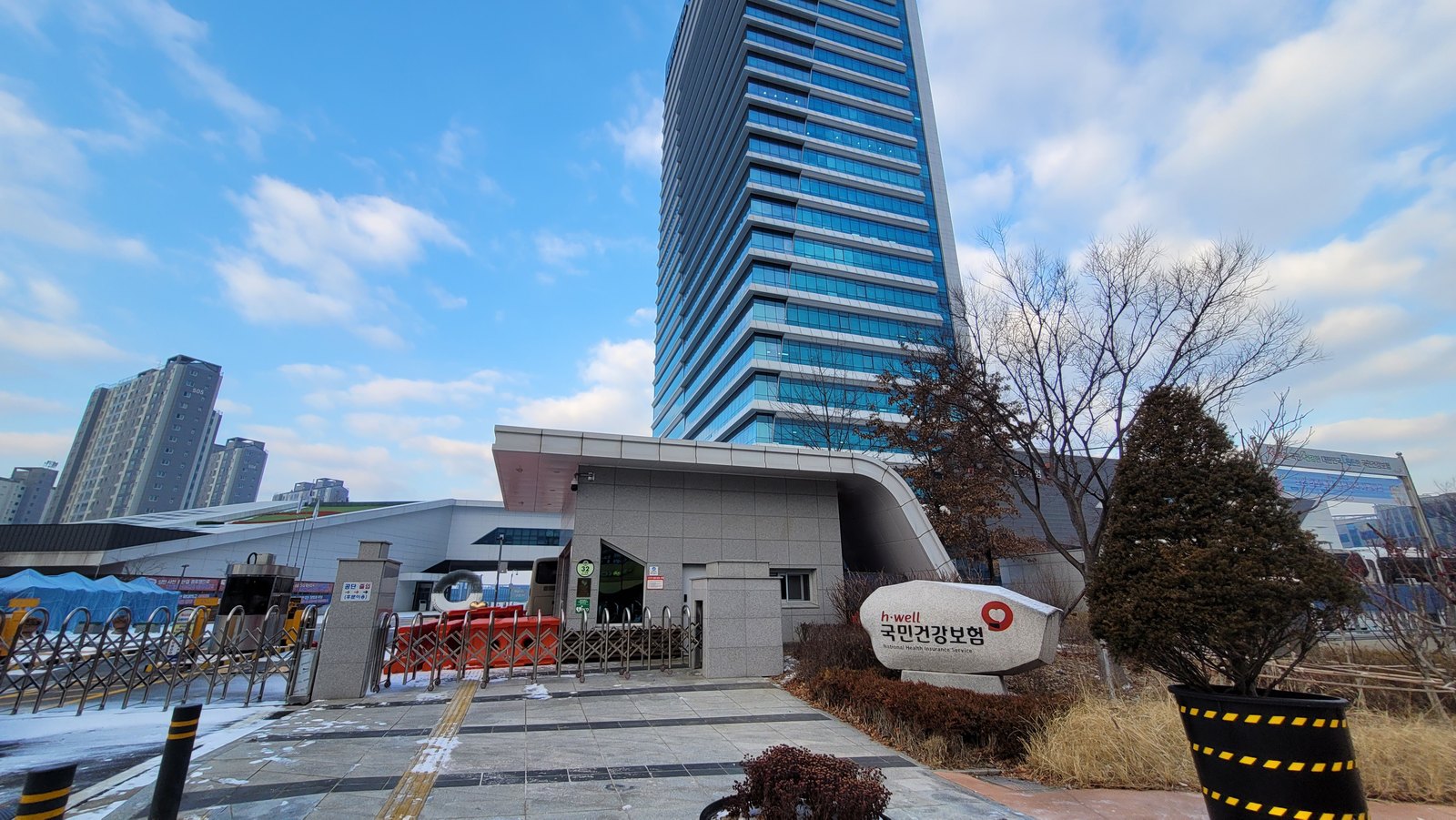 The National Health Insurance Service headquarters tower in Wonju with the corporate stone sign at the entrance plaza