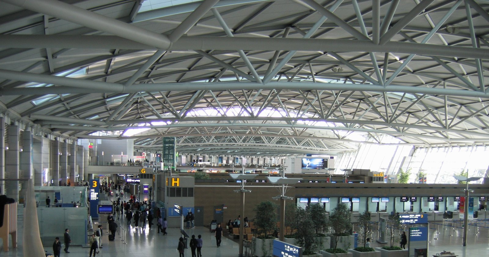 The departure hall of Incheon International Airport Terminal 1 seen from an upper level, with its lattice roof and check-in counters