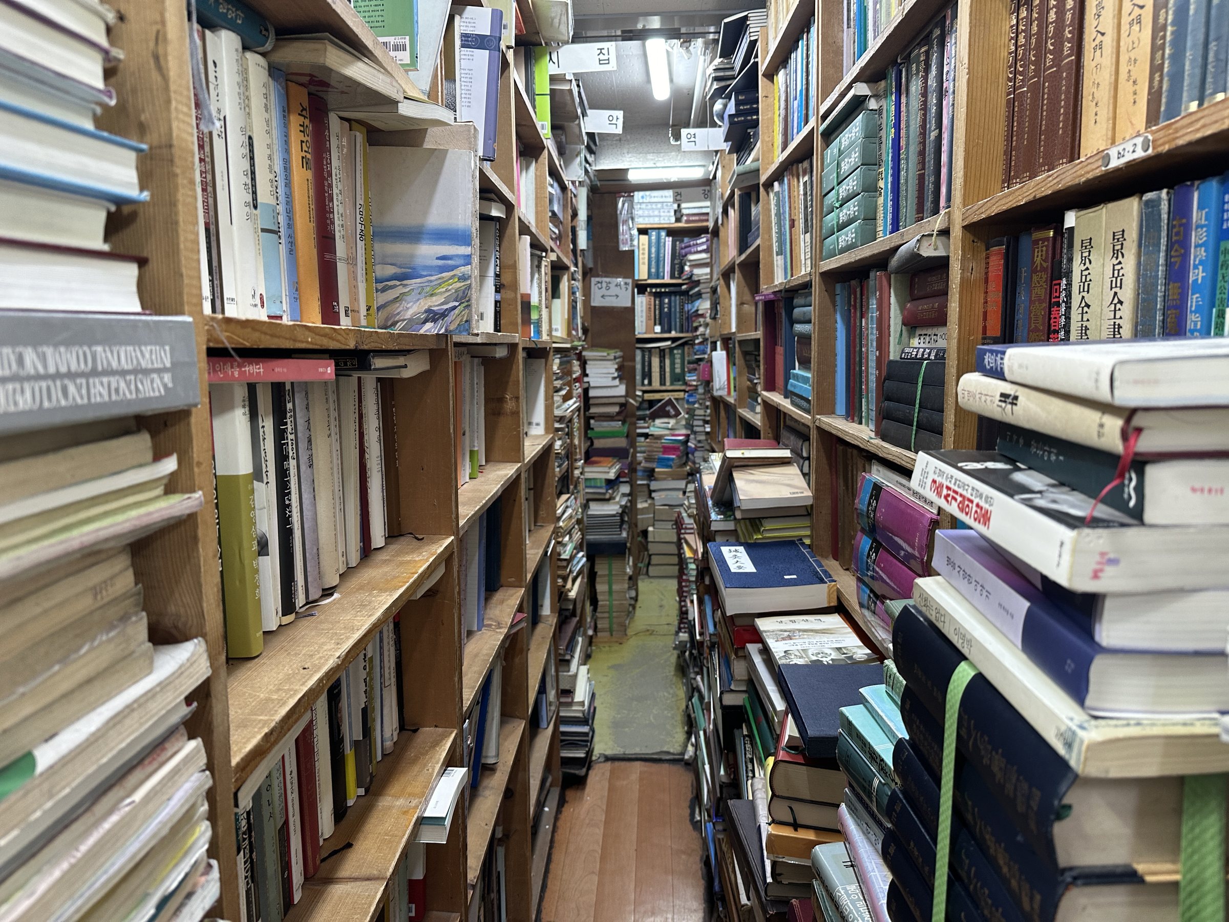 Narrow aisle of a used-book store in Seoul stacked floor to ceiling with secondhand books